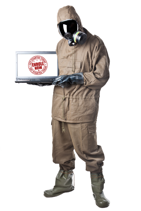 A man in a gas mask and overalls holding a laptop.