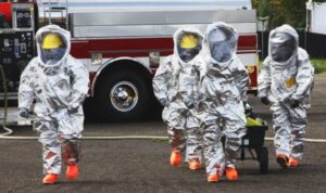 A group of people in hazmat suits next to a fire truck.